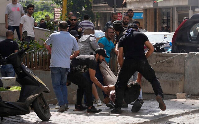 Supporters of a Shiite group allied with Hezbollah help an injured comrade during armed clashes that erupted during a protest in the southern Beirut suburb of Dahiyeh, Lebanon, on Thursday, October 14, 2021. It was not immediately clear what triggered the gunfire, but tensions were high along a former civil war front-line between Muslim Shiite and Christian areas. (AP Photo/Hassan Ammar) Supporters of a Shiite group allied with Hezbollah help an injured comrade during armed clashes that erupted during a protest in the southern Beirut suburb of Dahiyeh, Lebanon, on Thursday, October 14, 2021. It was not immediately clear what triggered the gunfire, but tensions were high along a former civil war front-line between Muslim Shiite and Christian areas. (AP Photo/Hassan Ammar)