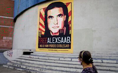 A pedestrians walks near a poster asking for the freedom of Colombian businessman and Venezuelan special envoy Alex Saab, in Caracas, Venezuela, October 16, 2021. (Ariana Cubillos/AP)