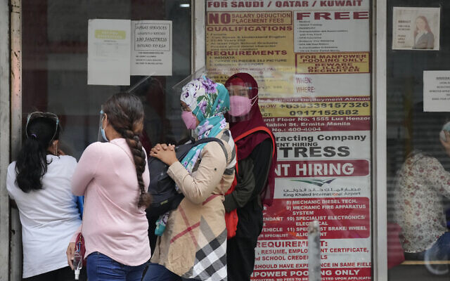 Women stand beside a sign about hiring domestic helpers for the Middle East outside an office in Manila, Philippines, October 18, 2021. (AP Photo/Aaron Favila) Women stand beside a sign about hiring domestic helpers for the Middle East outside an office in Manila, Philippines, October 18, 2021. (AP Photo/Aaron Favila)