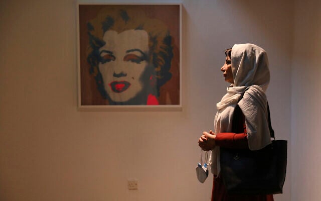 Fatemeh Rezaei, a retired teacher, stands next to a Marilyn Monroe portrait by American artist Andy Warhol at Tehran Museum of Contemporary Art in Tehran, Iran, on October 19, 2021. (AP Photo/Vahid Salemi)