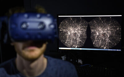 In this Oct. 12, 2021 file photo, Hadrien Gurnel, software engineer at EPFL's Laboratory for Experimental Museology (eM+) explores with a virtual reality helmet the most detailed 3D map of the universe with the virtual reality software VIRUP, Virtual Reality Universe Project developed by Swiss Federal Institute of Technology, in St-Sulpice near Lausanne, Switzerland.  (Laurent Gillieron/Keystone via AP)