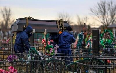 Gravediggers carry a coffin with a body of a patient who died of coronavirus at the Novo-Yuzhnoye cemetery, which serves as one of the burial grounds for those who died of the coronavirus outside Omsk, Russia, Oct. 22, 2021 (AP Photo)