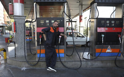 A worker leans against a gasoline pump that has been turned off, at a gas station in Tehran, Iran, on Tuesday, October 26, 2021. (AP Photo/Vahid Salemi)