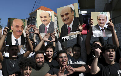 Supporters of Samir Geagea, the leader of the Christian Lebanese Forces party, chant slogans as they hold his photo after he declined to show up for questioning over deadly clashes in Beirut earlier this month, outside his residence in Maarab, east of Beirut, Lebanon, October 27, 2021. (Bilal Hussein/AP)