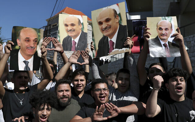 Supporters of Samir Geagea, the leader of the Christian Lebanese Forces party, chant slogans as they hold his photo after he declined to show up for questioning over deadly clashes in Beirut earlier this month, outside his residence in Maarab, east of Beirut, Lebanon, October 27, 2021. (AP Photo/Bilal Hussein)
