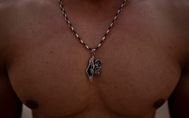 A Palestinian man wearing a necklace with a pendant symbolizing Palestinian national identity poses for a photo on the beach of Gaza City, Sept. 10, 2021. (AP Photo/Khalil Hamra)