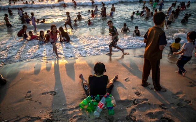 A Palestinian boy uses empty plastic bottles to flood while swimming, rests on the beach of Gaza City, July 9, 2021. (AP Photo/Khalil Hamra)
