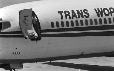 A Shiite Muslim hijacker armed with a Soviet-made AK-47 rifle looks from the open door of the Trans World Airlines jet held at Beirut International Airport in Lebanon, Wednesday, June 19, 1985.  (AP Photo/Herve Merliac)