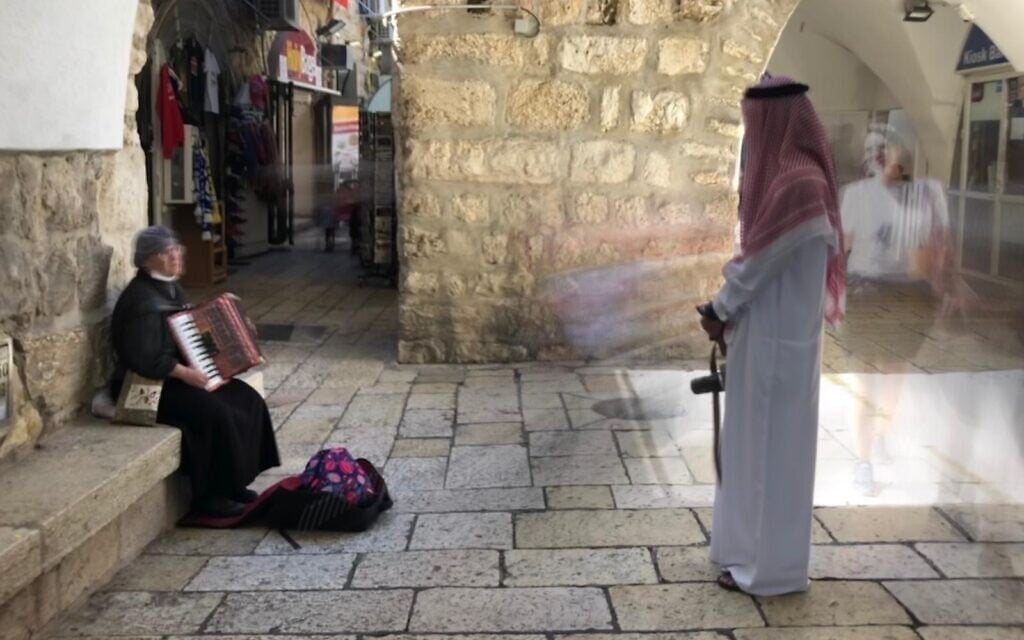 Bahraini activist Mohammed Al Shaer listens to a street musician in Jerusalem's Jewish Quarter, October 6, 2021 (Lazar Berman, Times of Israel)