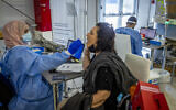 A healthcare worker takes a swab sample from a woman for COVID-19, after returning from overseas at the Ben Gurion International Airport on September 20, 2021. (Nati Shohat/Flash90)