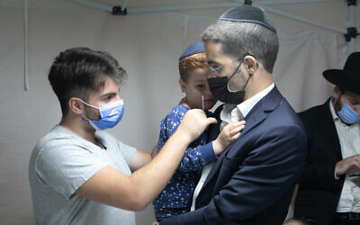 An ultra-Orthodox man has his son tested for COVID-19 in in Lod, on October 17, 2021. (Yossi Aloni/Flash90)
