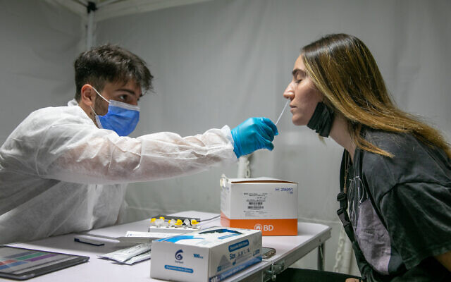 A medical employee takes a COVID-19 rapid antigen sample in Lod on October 17, 2021. (Yossi Aloni/Flash90) A medical employee takes a COVID-19 rapid antigen sample in Lod on October 17, 2021. (Yossi Aloni/Flash90)