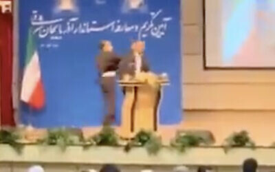 In this screen capture from video aired by Iranian state television on October 23, 2021, an unidentified mans slaps Eastern Azerbaijan Governor Abedin Khorram as he speaks in the provincial capital Tabriz. (Screenshot/Twitter)