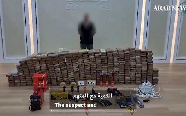 A suspect in a major drug bust in the United Arab Emirates is photographed alongside the haul by police -- some 500 kilograms of cocaine -- on October 10, 2021 (screenshot: Arab News)