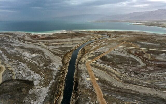 A picture taken in the area of Ein Gedi shows the Araba River crossing a dried-up sea stretch which exposed and created a salt plain, on its way to the southern part of Dead Sea, January 15, 2021. (Menahem KAHANA / AFP) A picture taken in the area of Ein Gedi shows the Araba River crossing a dried-up sea stretch which exposed and created a salt plain, on its way to the southern part of Dead Sea, January 15, 2021. (Menahem KAHANA / AFP)
