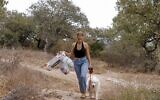 Elishya Ben Meir, an 18-year-old Israeli, safely disposes of abandoned waste after registering it on the 'Clean Coin' mobile application as she walks her dog in the town of Kiryat Tiv'on near Israel's northern city of Haifa on October 20, 2021 (JACK GUEZ / AFP)