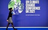 A participant walks past a COP26 UN Climate Change Conference' poster on the first day of the COP26 UN Climate Change Conference at the Scottish Event Campus (SEC) in Glasgow, Scotland, on October 31, 2021. (ALAIN JOCARD / AFP)