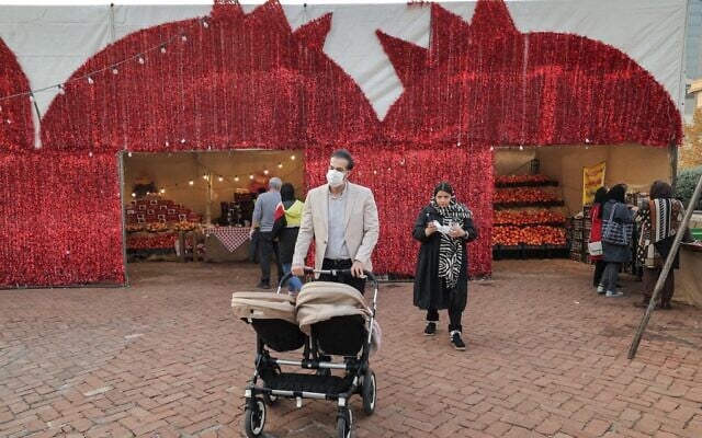A man pushes a twin stroller during the Pomegranate Festival in Iran's capital Tehran on November 14, 2021. (ATTA KENARE / AFP) A man pushes a twin stroller during the Pomegranate Festival in Iran's capital Tehran on November 14, 2021. (ATTA KENARE / AFP)