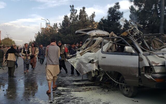 Residents gather next to a damaged minibus after a bomb blast where two people were killed and five wounded in Kabul, on November 17, 2021. (AFP) Residents gather next to a damaged minibus after a bomb blast where two people were killed and five wounded in Kabul, on November 17, 2021. (AFP)