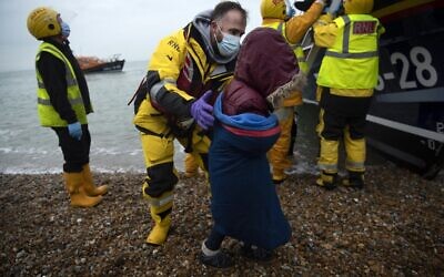 Migrants are helped ashore from a RNLI (Royal National Lifeboat Institution) lifeboat at a beach in Dungeness, on the south-east coast of England, on November 24, 2021, after being rescued while crossing the English Channel. (Ben STANSALL / AFP)