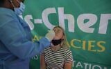 A healthcare worker conducts a polymerase chain reaction (PCR) COVID-19 test on a traveler at OR Tambo International Airport in Johannesburg on November 27, 2021, after several countries banned flights from South Africa following the discovery of a new COVID-19 variant Omicron. (Phill Magakoe / AFP)