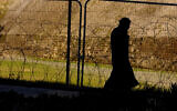 A woman protects her face from the cold as she walks by the "Green Line" with barbed wire and fences at the Greek controlled area by the UN buffer zone and in the divided capital Nicosia in the eastern Mediterranean island of Cyprus, Monday 9, 2017. (AP/Petros Karadjias)