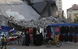 Women shop next to the rubble of destroyed buildings hit by Israeli airstrikes during an 11-day war between Gaza's Hamas rulers and Israel, at the main shopping road in Gaza City, Thursday, Sept. 23, 2021. (AP/Adel Hana)