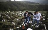 Relatives of Luis Enrique Rodriguez, who died of COVID-19, visit where he was buried on a hill at the El Pajonal de Cogua Natural Reserve, in Cogua, north of Bogota, Colombia, October 25, 2021. (AP Photo/Ivan Valencia)