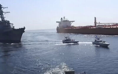 This frame grab from a video shows Iranian Revolutionary Guard speed boats, center, in front of a US warship, left, amid the seizure of a Vietnamese-flagged oil tanker, right, in the Gulf of Oman on November 3, 2021. (Revolutionary Guard via AP)