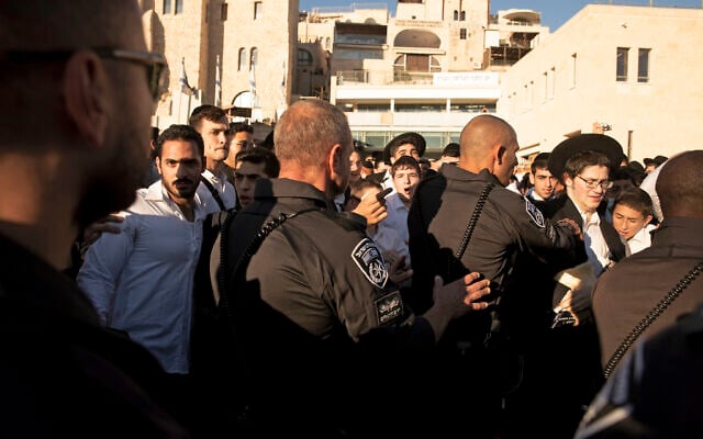 Police scuffle with utra-Orthodox Jews during a protest against the group Women of the Wall holding their Rosh Hodesh, or new month prayer at the Western Wall, the holiest site where Jews can pray, in the Old City of Jerusalem, Friday, Nov. 5, 2021. (AP Photo/Maya Alleruzzo)
