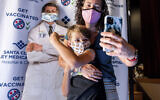 A mother poses with her son in front of a picture of Dr. Anthony Fauci, after the boy received a Pfizer COVID-19 vaccine in San Jose, California, November 3, 2021. (Noah Berger/AP)