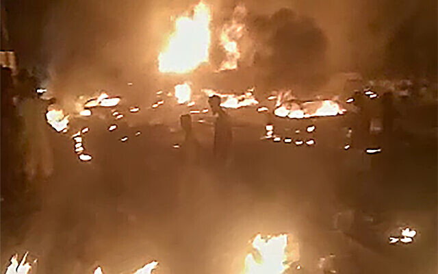 In this image made from video, people walk by burning debris following the explosion of an oil tanker in the Wellington suburb of Sierra Leone's capital Freetown, on November 5, 2021. (AP Photo) In this image made from video, people walk by burning debris following the explosion of an oil tanker in the Wellington suburb of Sierra Leone's capital Freetown, on November 5, 2021. (AP Photo)