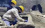 Archaeologists are seen cleaning up their latest finding in Pompeii, Italy, in an image released November 6, 2021. (AP Photo)