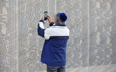 A person takes a photo of the engraved name of his grandfather at the Shoah Wall of Names Memorial who was a victim of the NS regime in Vienna, Austria, Nov. 9, 2021 (AP Photo/Lisa Leutner)