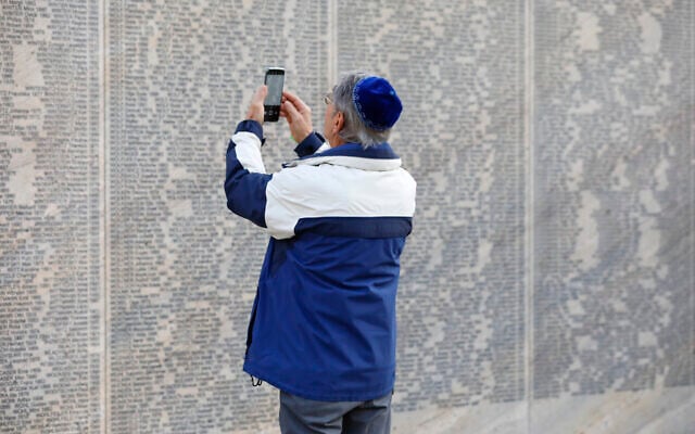 A person takes a photo of the engraved name of his grandfather at the Shoah Wall of Names Memorial who was a victim of the NS regime in Vienna, Austria, Nov. 9, 2021 (AP Photo/Lisa Leutner)