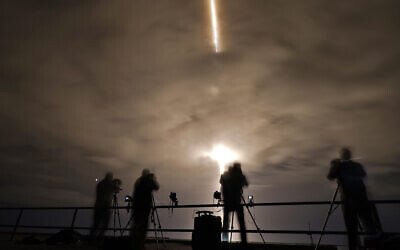 Photographers are silhouetted as a SpaceX Falcon 9 rocket with the Crew Dragon attached lifts off on November 10, 2021, at the Kennedy Space Center in Cape Canaveral, Florida. (AP Photo/Chris O'Meara)
