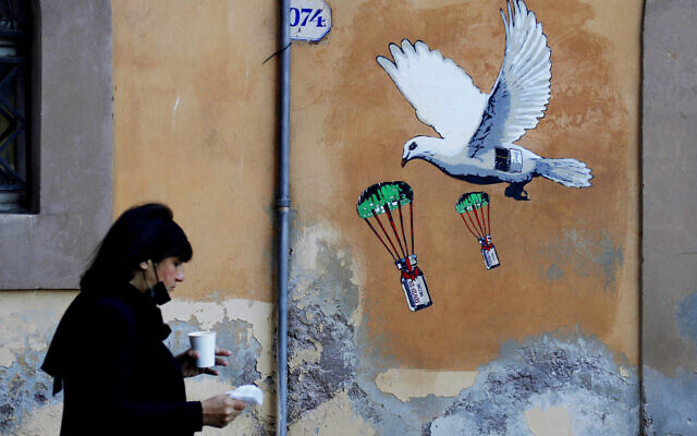 A woman walks past a mural depicting a white dove parachuting COVID-19 vaccine vials, posted near the Italian Health Ministry Headquarters in Rome, April 4, 2021. (AP/Gregorio Borgia, file) A woman walks past a mural depicting a white dove parachuting COVID-19 vaccine vials, posted near the Italian Health Ministry Headquarters in Rome, April 4, 2021. (AP/Gregorio Borgia, file)