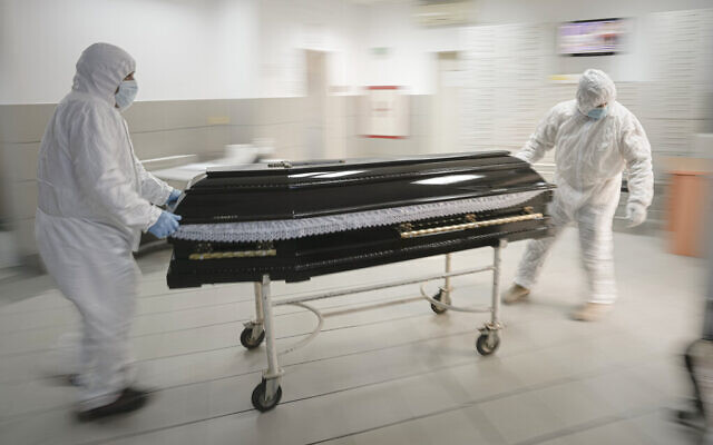 Funeral house employees drag a coffin on a trolley as they arrive at the University Emergency Hospital morgue to take a COVID-19 victim for burial, in Bucharest, Romania, on November 8, 2021. (AP Photo/Vadim Ghirda, File)