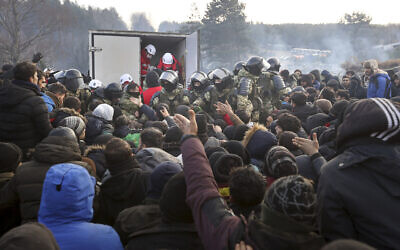 Belarusian servicemen control the situation while migrants get humanitarian aid as they gather at the Belarus-Poland border near Grodno, Belarus, Nov. 12, 2021 (Ramil Nasibulin/BelTA pool photo via AP)