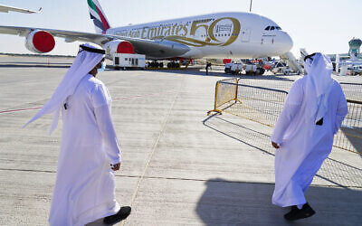 Two Emiratis walk toward an Emirates Airbus A380 jumbo jet on display at the Dubai Air Show in Dubai, United Arab Emirates, November 14, 2021. (AP Photo/Jon Gambrell)