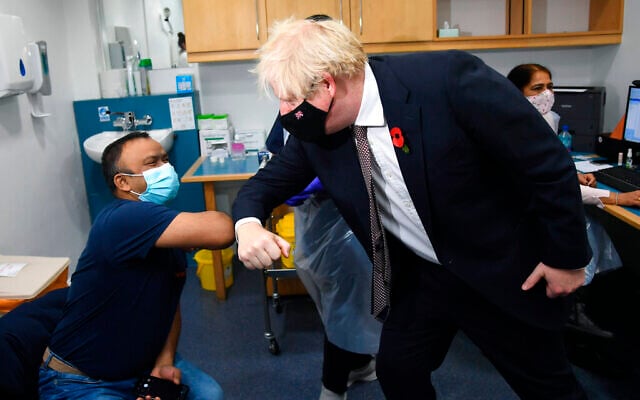 Britain's Prime Minister Boris Johnson gestures with Arzou Miah, as he visits the Woodgrange GP Surgery vaccination center, in East London, Monday, Nov. 15, 2021. (Jeremy Selwyn, Pool Photo via AP)
