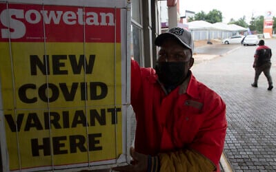 A gas station attendant stands next to a newspaper headline in Pretoria, South Africa, Nov. 27, 2021. (Denis Farrell/AP)