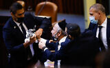 Shas MK Moshe Abutbul is escorted out of the Knesset on November 3, 2021. (Olivier Fitoussi/Flash90)