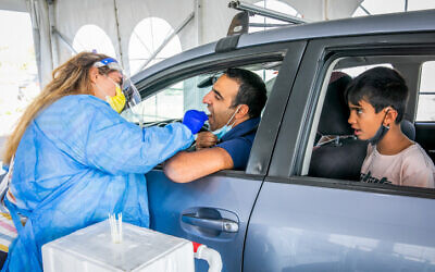 Healthcare workers take samples at a drive through complex for coronavirus testing, in Modi'in, on November 10, 2021 (Yossi Aloni/Flash90)