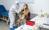 A medical team member wearing protective gear swabs an Israeli traveler to test for COVID-19 in Rome, Italy, on November 11, 2021. (Yahav Gamliel/Flash90)