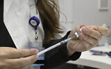 An Israeli health worker prepares a coronavirus vaccine shot against COVID-19, at a health clinic in Katzrin, on November 16, 2021. (Michael Giladi/Flash90)