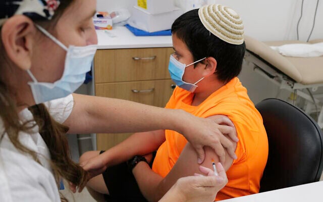 An Israeli child receives a COVID-19 vaccine at a Maccabi vaccination center in Katzrin on November 24, 2021. (Michael Giladi/Flash90) An Israeli child receives a COVID-19 vaccine at a Maccabi vaccination center in Katzrin on November 24, 2021. (Michael Giladi/Flash90)