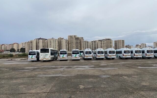 Buses parked at what was once Jerusalem Airport at Atarot; in the background, the high-rises of the Kafr Aqab neighborhood -- formally part of Jerusalem but outside the security barrier, November 2021. (DH / Times of Israel)