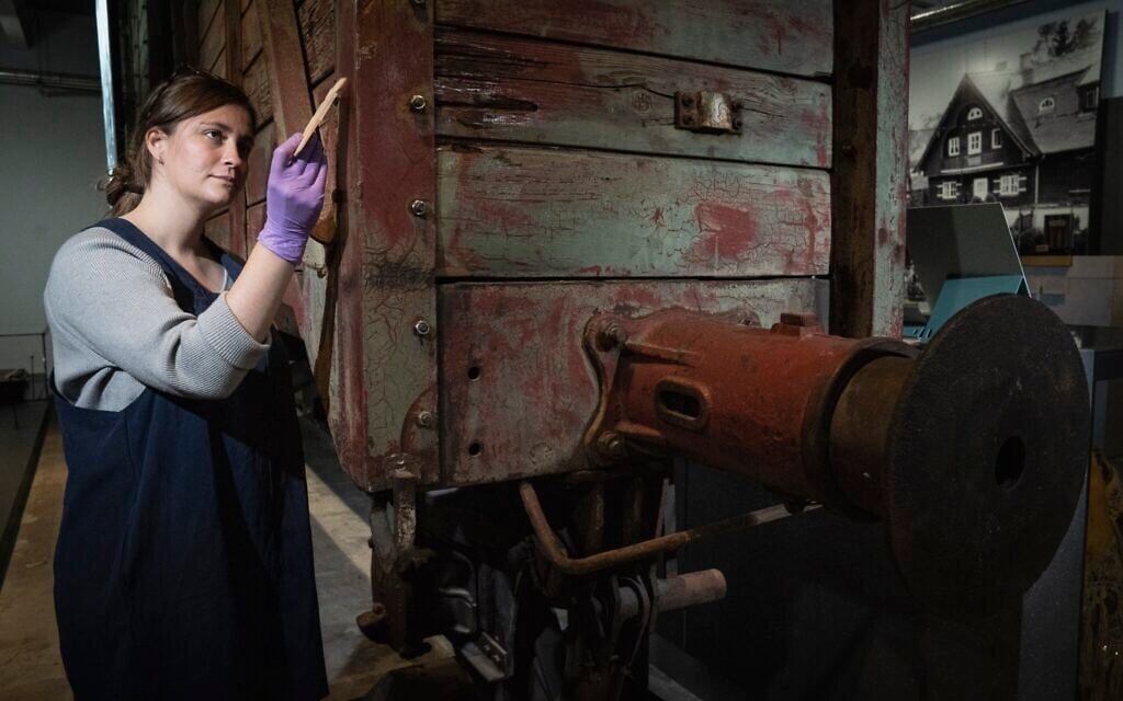 Preservation technician Emily Thomas cleans a rail wagon of the type used to transport victims to death camps at the Holocaust Gallery at the Imperial War Museum in London, September 30, 2021. (Courtesy of the Imperial War Museum)