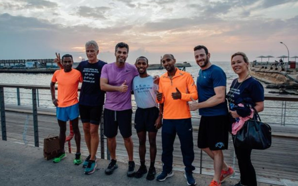 UAE ambassador to Israel Mohamed Al Khaja (third from left), runner Avi Solomon (center), and Times of Israel diplomatic correspondent Lazar Berman (second from right) before their run in Tel Aviv, November 18, 2021 (Maria Troyanker/UAE Embassy)